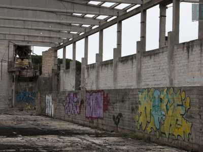 I lati dell'edificio sono caratterizzati da un'incalzante vegetazione spontanea e pareti marchiate da colorati graffiti
